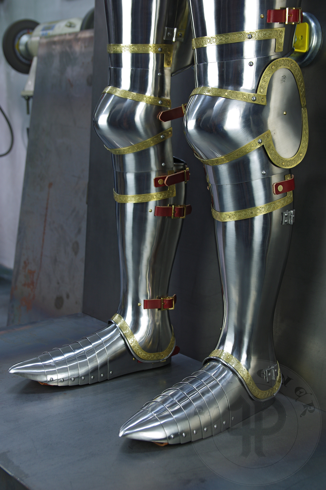 Complete leg harness mainly inspired by depicts from Altar of St George of the Valencian school, circa 1410. Cuisses are quite unusual with such detail like lames on upper part of thigh plates and stop ribs. They are also closed at the back like in English style armour. All made of medium carbon steel and heat hardened and tempered up to 42 HRC./Pene osony ng gwnie inspirowane przedstawieniami z otarza w. Jerzego z warsztatu z Walencji, okoo 1410 rok. Nabiodrki s do nietypowe z takimi detalami jak dodatkowe folgi oraz kute wzmocnienie ochronne. S one take w peni zamknite podobnie jak w angielskim stylu. Wykonane w caoci ze stali redniowglowej oraz hartowane i odpuszczane do twardoci 42 HRC.