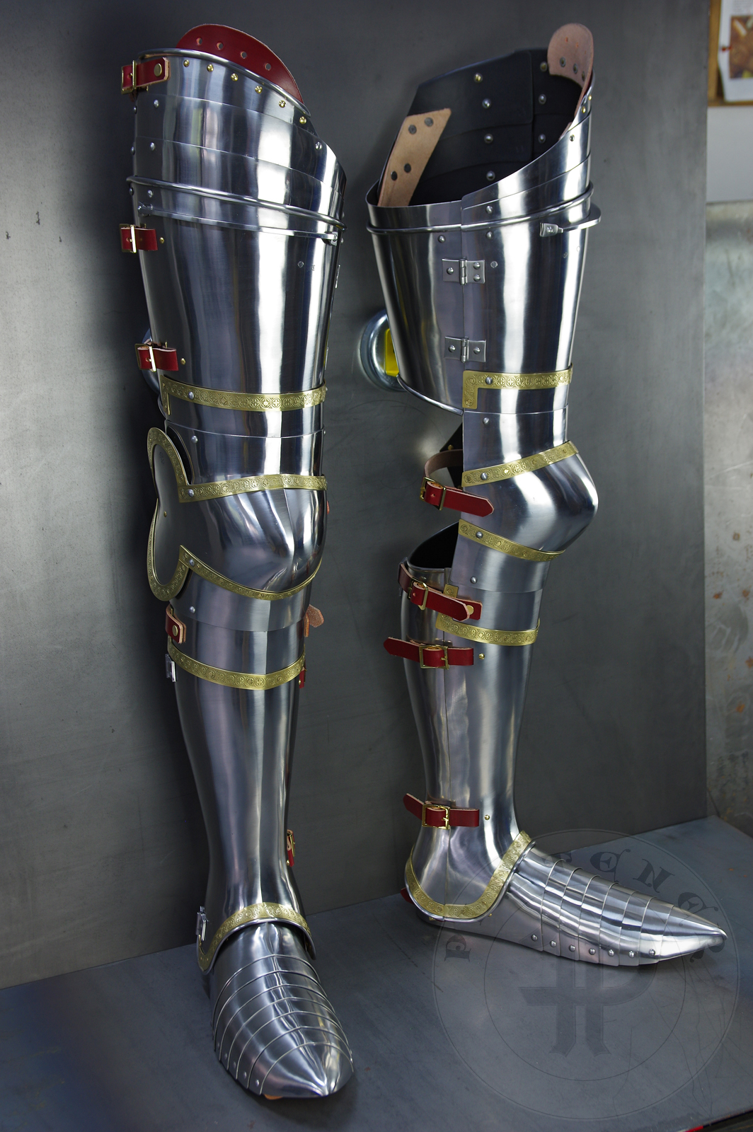 Complete leg harness mainly inspired by depicts from Altar of St George of the Valencian school, circa 1410. Cuisses are quite unusual with such detail like lames on upper part of thigh plates and stop ribs. They are also closed at the back like in English style armour. All made of medium carbon steel and heat hardened and tempered up to 42 HRC./Pene osony ng gwnie inspirowane przedstawieniami z otarza w. Jerzego z warsztatu z Walencji, okoo 1410 rok. Nabiodrki s do nietypowe z takimi detalami jak dodatkowe folgi oraz kute wzmocnienie ochronne. S one take w peni zamknite podobnie jak w angielskim stylu. Wykonane w caoci ze stali redniowglowej oraz hartowane i odpuszczane do twardoci 42 HRC.