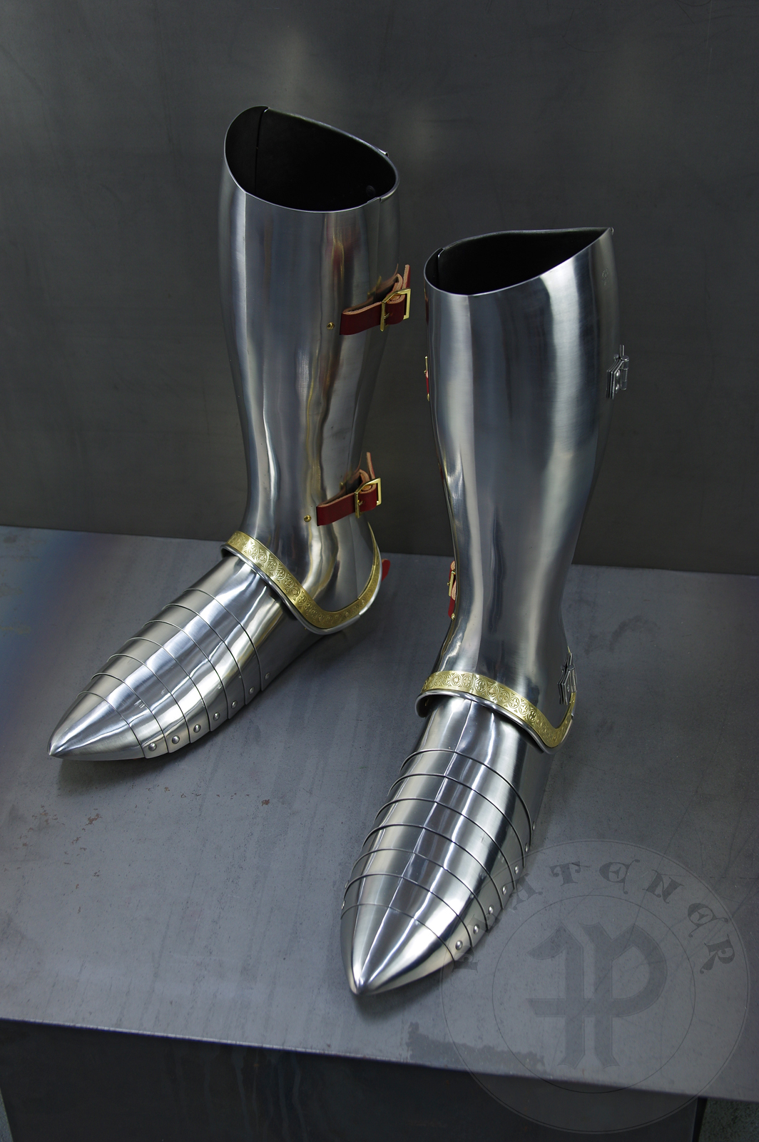 Complete leg harness mainly inspired by depicts from Altar of St George of the Valencian school, circa 1410. Cuisses are quite unusual with such detail like lames on upper part of thigh plates and stop ribs. They are also closed at the back like in English style armour. All made of medium carbon steel and heat hardened and tempered up to 42 HRC./Pene osony ng gwnie inspirowane przedstawieniami z otarza w. Jerzego z warsztatu z Walencji, okoo 1410 rok. Nabiodrki s do nietypowe z takimi detalami jak dodatkowe folgi oraz kute wzmocnienie ochronne. S one take w peni zamknite podobnie jak w angielskim stylu. Wykonane w caoci ze stali redniowglowej oraz hartowane i odpuszczane do twardoci 42 HRC.