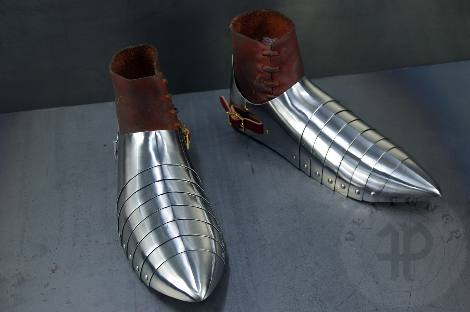 Complete leg harness mainly inspired by depicts from Altar of St George of the Valencian school, circa 1410. Cuisses are quite unusual with such detail like lames on upper part of thigh plates and stop ribs. They are also closed at the back like in English style armour. All made of medium carbon steel and heat hardened and tempered up to 42 HRC./Pene osony ng gwnie inspirowane przedstawieniami z otarza w. Jerzego z warsztatu z Walencji, okoo 1410 rok. Nabiodrki s do nietypowe z takimi detalami jak dodatkowe folgi oraz kute wzmocnienie ochronne. S one take w peni zamknite podobnie jak w angielskim stylu. Wykonane w caoci ze stali redniowglowej oraz hartowane i odpuszczane do twardoci 42 HRC.
