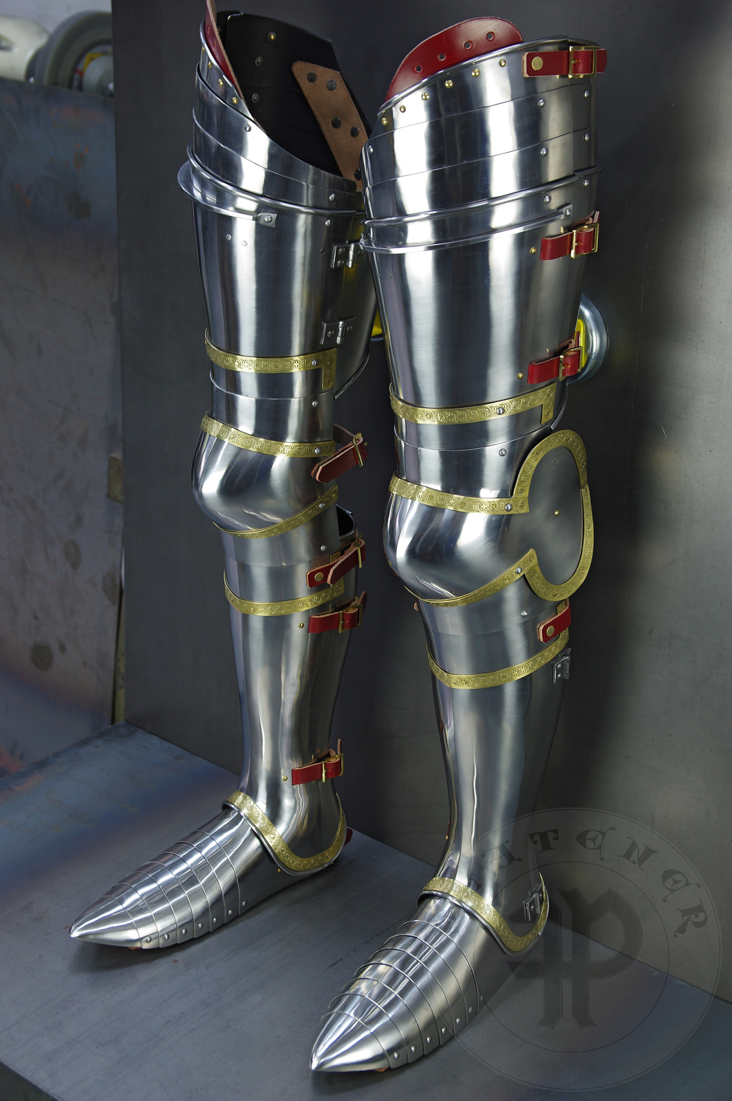 Complete leg harness mainly inspired by depicts from Altar of St George of the Valencian school, circa 1410. Cuisses are quite unusual with such detail like lames on upper part of thigh plates and stop ribs. They are also closed at the back like in English style armour. All made of medium carbon steel and heat hardened and tempered up to 42 HRC./Pene osony ng gwnie inspirowane przedstawieniami z otarza w. Jerzego z warsztatu z Walencji, okoo 1410 rok. Nabiodrki s do nietypowe z takimi detalami jak dodatkowe folgi oraz kute wzmocnienie ochronne. S one take w peni zamknite podobnie jak w angielskim stylu. Wykonane w caoci ze stali redniowglowej oraz hartowane i odpuszczane do twardoci 42 HRC.