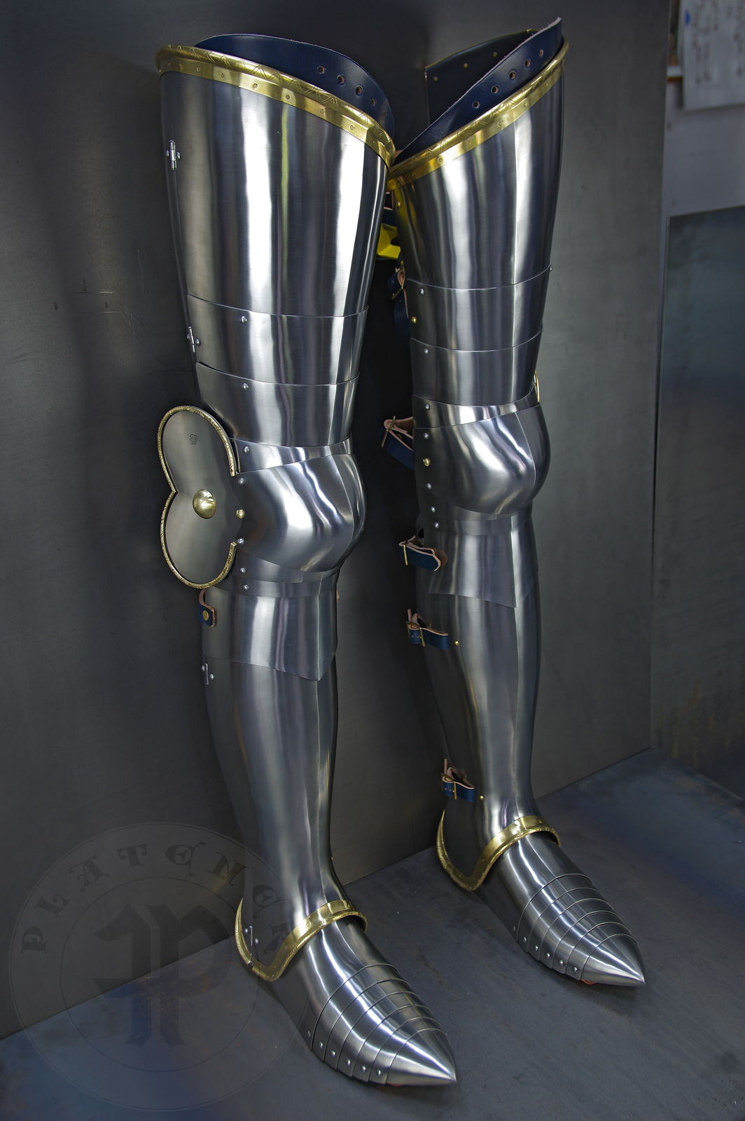 Late 14th/early 15th c. style full plate leg harness with brass decorations with a geometrical, hand filed pattern. Material: medium carbon and spring steel of various thickness: 1 mm; 1,2 mm and 1,5 mm; brass; vegetable tanned leather. Heat treatment: cuisses (thigh plates, lames, poleyns and demi-graves) heat hardened and tempered up to 42 HRC.