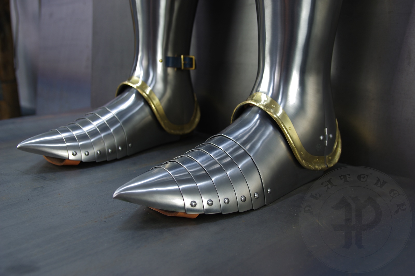 Late 14th/early 15th c. style full plate leg harness with brass decorations with a geometrical, hand filed pattern. Material: medium carbon and spring steel of various thickness: 1 mm; 1,2 mm and 1,5 mm; brass; vegetable tanned leather. Heat treatment: cuisses (thigh plates, lames, poleyns and demi-graves) heat hardened and tempered up to 42 HRC.